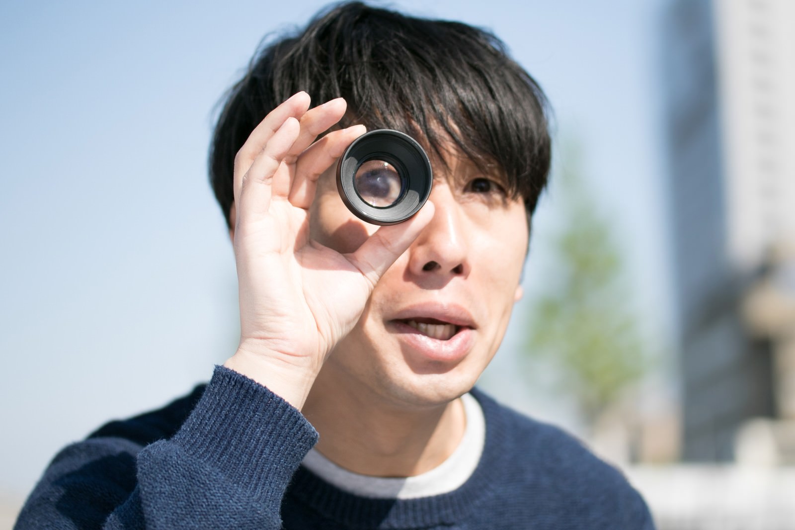 単眼鏡を片眼に当てて驚く表情の男性［モデル：大川竜弥］