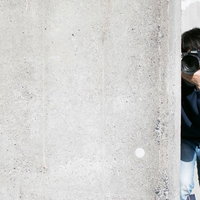コンクリート壁から顔を出すカメラマン男性による盗撮の写真
