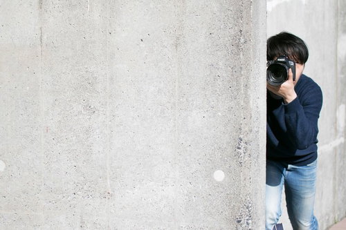 コンクリート壁から顔を出すカメラマン男性による盗撮