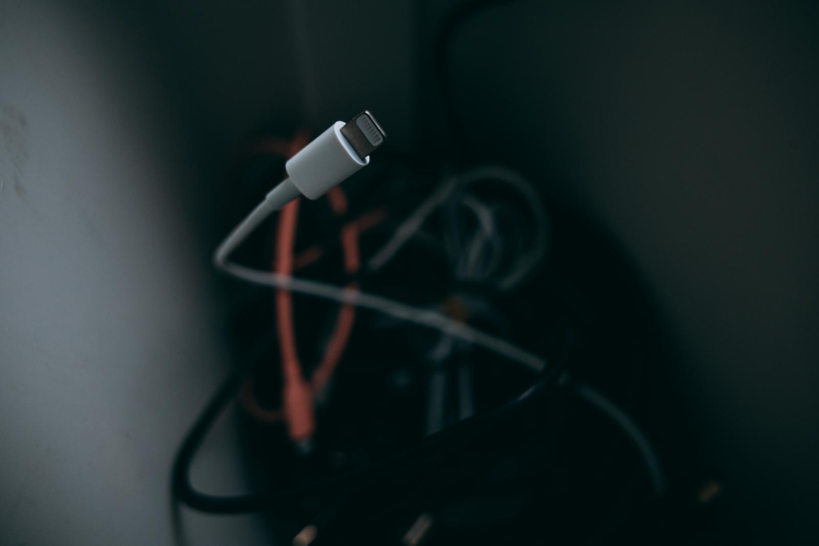 白いLightningケーブルコネクタと絡まったケーブル群