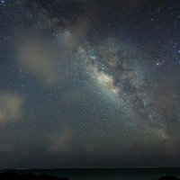 星々と天の川が輝く海岸線の夜空～砂浜と磯の夜間撮影の写真