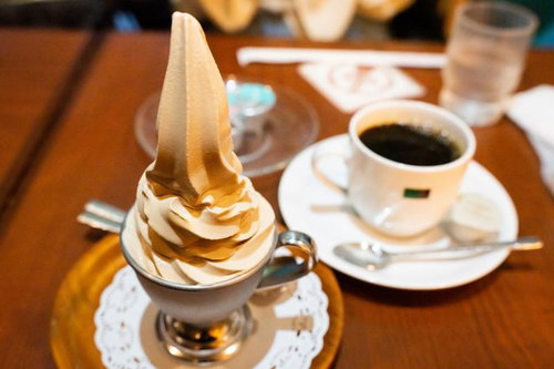 コーヒーカップにのせたバニラソフトクリームの写真
