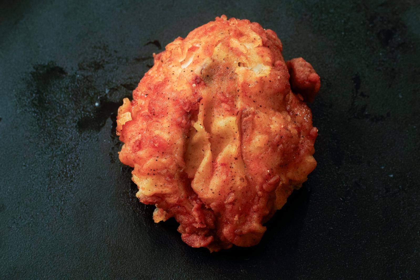 Freshly fried bone-in chicken legs on a black plate