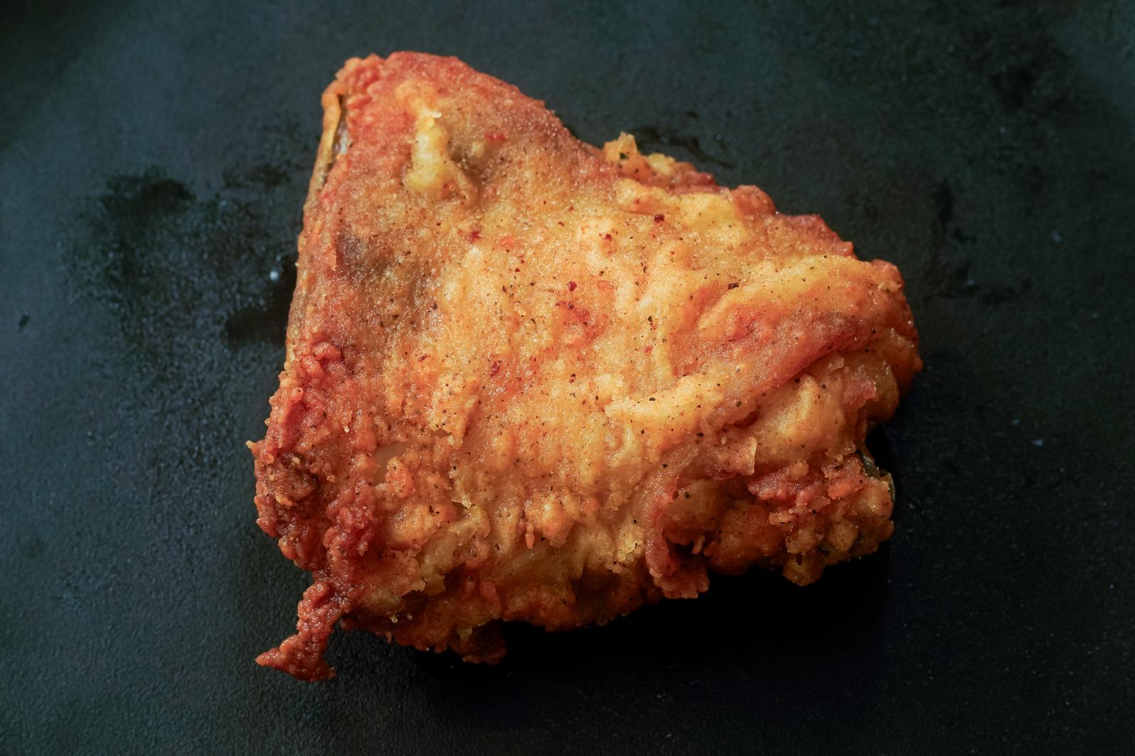 Crispy fried chicken thighs on a black plate