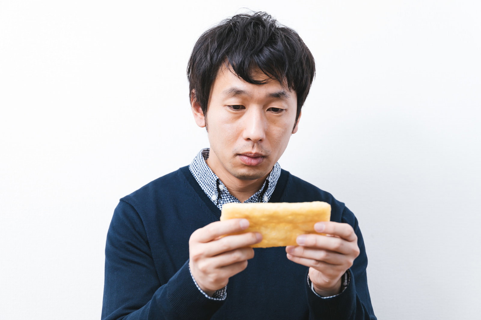 油揚げを両手で持ちスマホ操作のような仕草をする男性［モデル：大川竜弥］