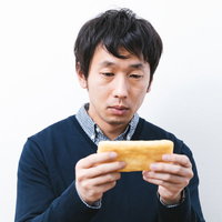 最新スマホが買えず油揚げでイメトレする倹約家男性の写真