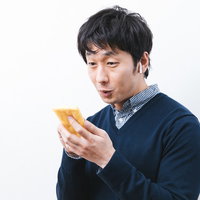 音楽を聴きながら油揚げを愛でる男性の写真