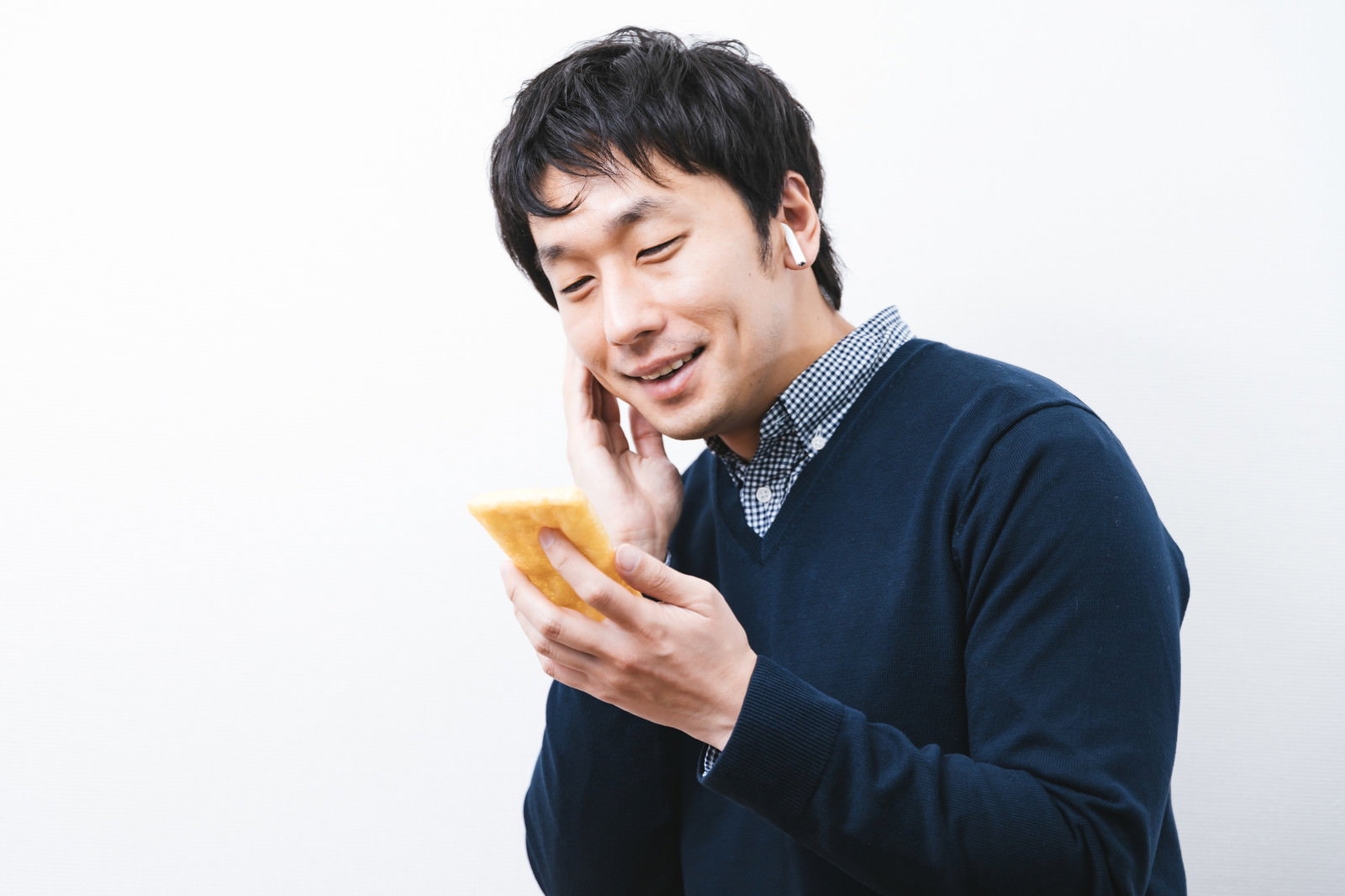 油揚げを手に持って笑う男性［モデル：大川竜弥］