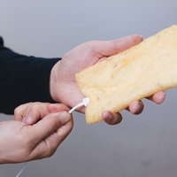 油揚げに充電ケーブルを挿す男性の手元の写真