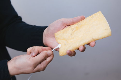 油揚げに充電ケーブルを挿す男性の手元