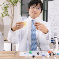 ビーカーの色味変化を確認して成功を喜ぶ研究員の写真