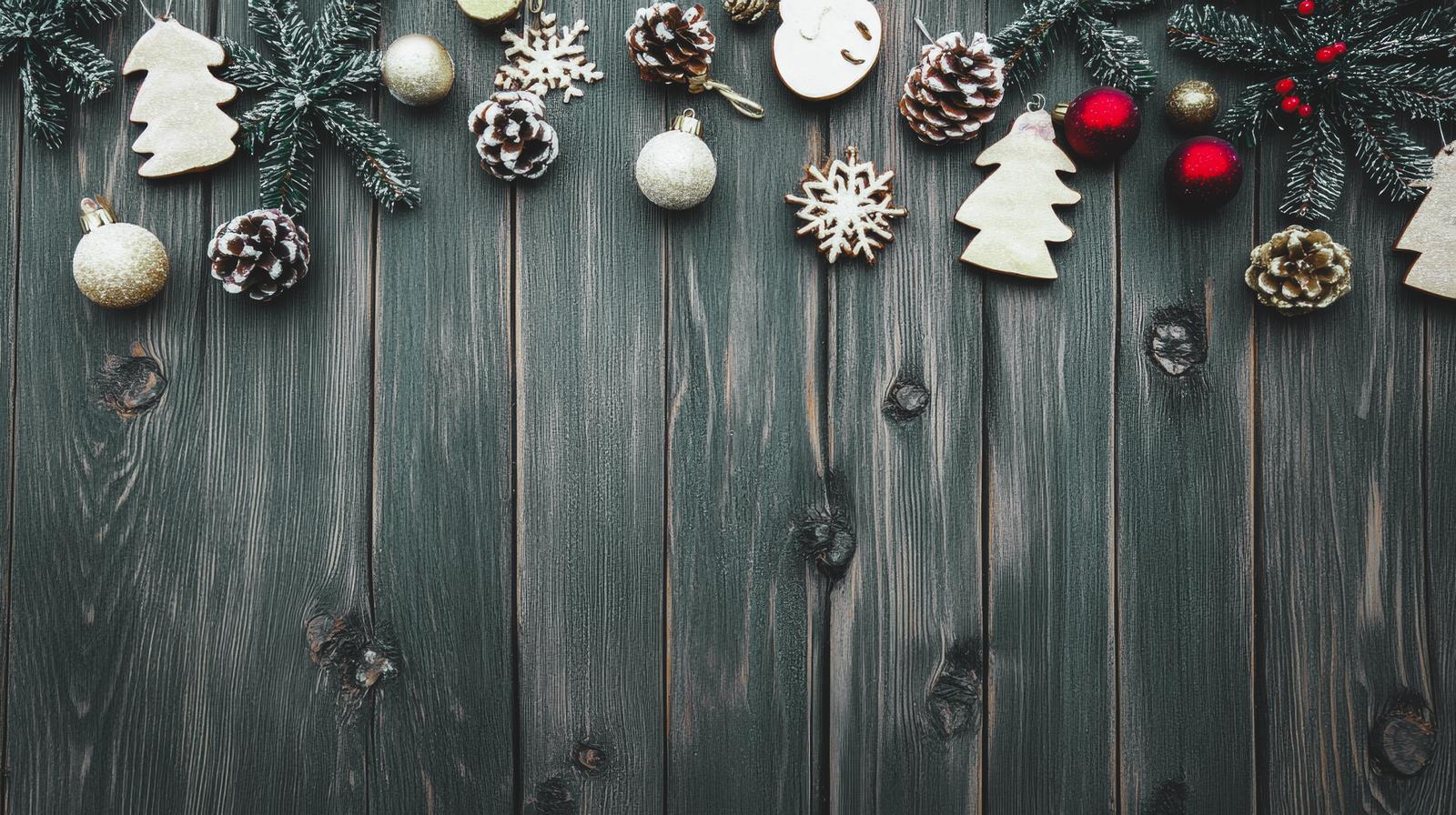 クリスマスオーナメントと木製ツリー、松ぼっくりを緑の木板に配置した装飾