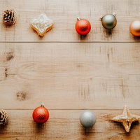 クリスマスの装飾が並ぶ木製テーブル上のオーナメントと松ぼっくりの写真