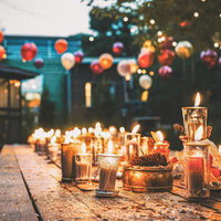 卓上に灯るキャンドルと色とりどりの装飾品が輝く夜間の屋外パーティー会場の写真