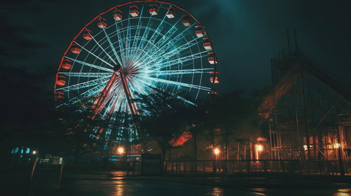 夜間に赤く発光する観覧車とお化け屋敷のホラースリル