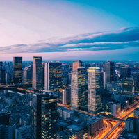 夕焼けに染まるビル群と車の流れ、都市交通の動きの写真