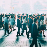 朝日に照らされた駅前の人であふれる出勤姿の写真