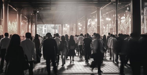 駅前の光に包まれた人混みと歩行者の混雑風景