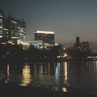 河岸のビル群の明かりが水面に映り込む夜景の写真