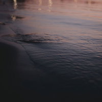 夕日を反射する波打ち際の光と波紋、砂浜に映る黄金色の光筋の写真