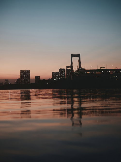 夕焼けに染まるお台場のレインボーブリッジと水面の反射