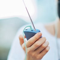 青空の下で携帯ラジオを聴く人のポートレートの写真