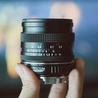 手に持つ味のあるオールドレンズの質感と刻印の写真