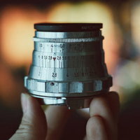 片手で持つオールドレンズの露出計スケールの写真