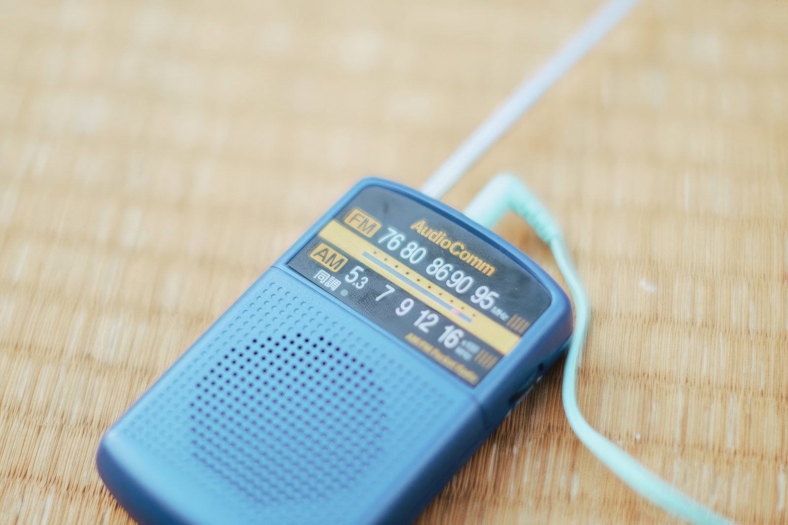 畳の上に置かれたFM・AM表示のある青いポケットラジオ