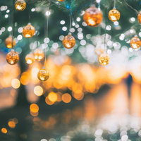 クリスマスの夜、緑の樹に吊るされたキラキラと煌めくゴールドのオーナメントボールの写真