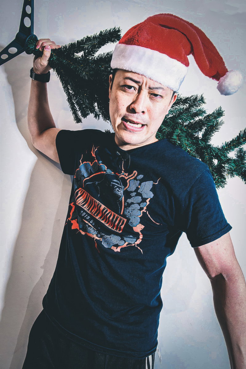サンタ帽の男性がクリスマスツリーを振り上げる［モデル：モデルリリース］