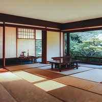 茶色の木枠に囲まれた広い畳のある和室、庭園の景色を望むの写真