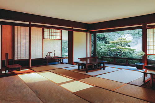 茶色の木枠に囲まれた広い畳のある和室、庭園の景色を望む