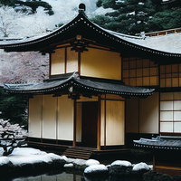 屋根に積もる初雪と池泉の日本家屋庭園の冬景色の写真