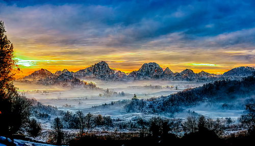 雪国の山々にオレンジ色の日が昇る朝焼けの情景