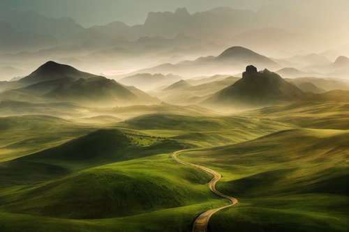 朝靄が立ち込める高原の丘から望む雄大な山並み