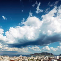 海沿いの街並みを望む入道雲と青空の夏の風景の写真