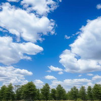 青空に流れる白い雲と緑の木々が連なる昼間の風景の写真