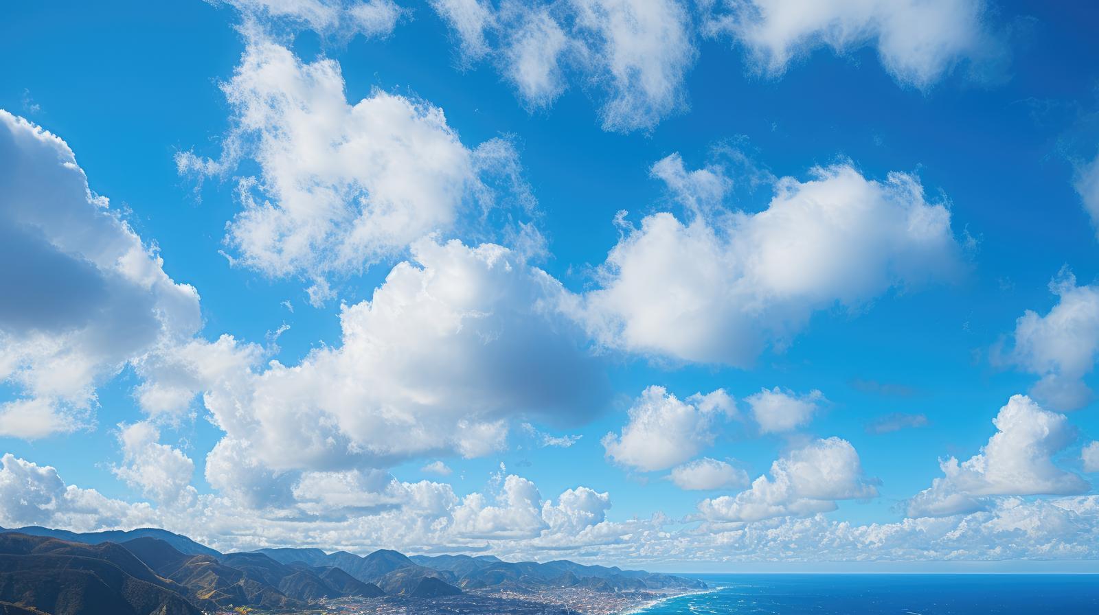 雲が浮かぶ青い空と海、遠くの山々が見える夏の風景