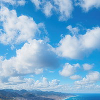 夏日の清々しい青空と雲海、海辺の山々と島々の風景の写真