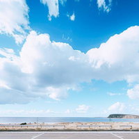 海岸前の広場から眺める雲湧く青空と島の風景の写真