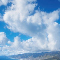 島の上に停滞する夏の入道雲と青い海の風景の写真