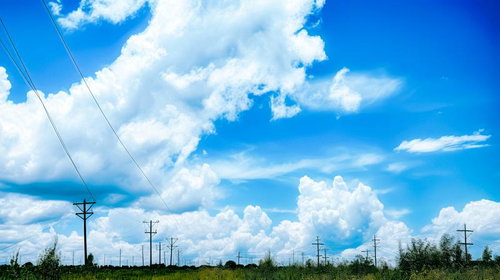 送電線と真夏日の積乱雲が立ち込める田園風景