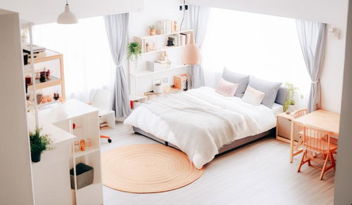 白とナチュラルカラーで統一した綺麗に整頓されたベッドのあるワンルーム