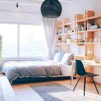 自然光がたっぷり入る本棚と木製家具のあるワンルームの写真