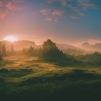 夕暮れの光に包まれた山々と草原の日没風景の写真