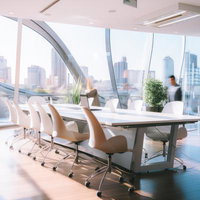 自然光が差し込む高層オフィスのデスクと都市景観の写真