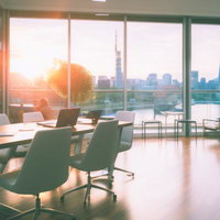 日没間際の高層オフィスビルの会議室でのビジネス打ち合わせシーンの写真