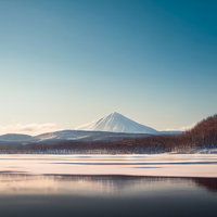 静寂な冬の湖畔と雪山の鏡面リフレクションの写真