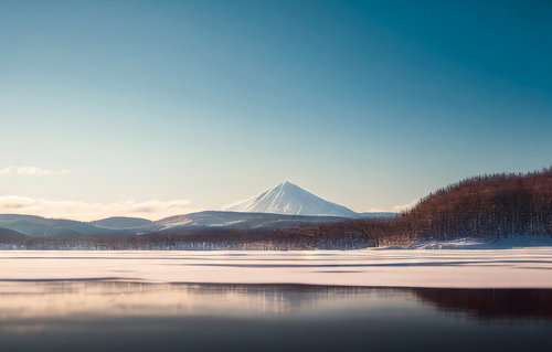 静寂な冬の湖畔と雪山の鏡面リフレクション